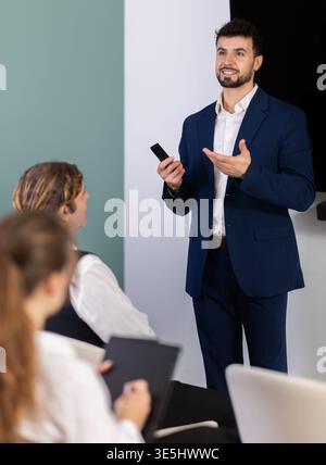 Male business trainer explaining topic to professionals using digital board Stock Photo