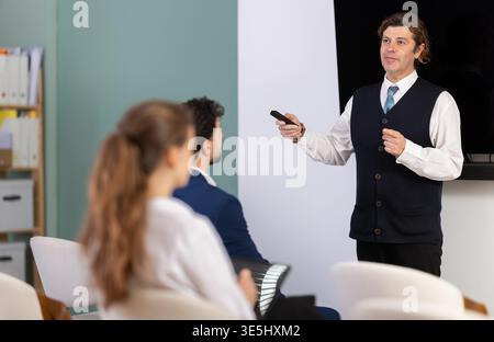Male business trainer explaining topic to professionals using digital board Stock Photo