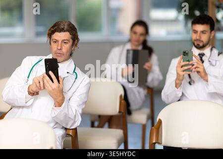 Medical students or doctors using mobile phones to scan QR-code during interactive lesson Stock Photo