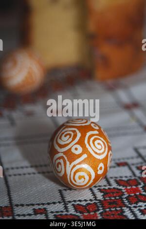 A festive Easter composition featuring two brown eggs decorated with white patterns and a sliced sweet Easter bread (paska) on a traditional embroider Stock Photo