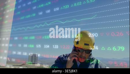 Holding phone worker wearing yellow hard hat standing in arid field with market overlay, copy space Stock Photo