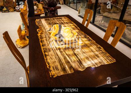 Petrified wood dining table with stone inlay surface paired with decorative onyx bowl in an interior setting Stock Photo