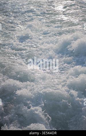 Waves crash on water surface during sunny day Stock Photo