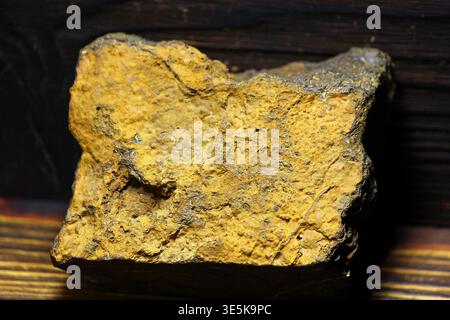 Rough yellow limonite iron ore specimen from Kaluga region, Russia, showcasing a textured mineral surface against a dark backdrop Stock Photo