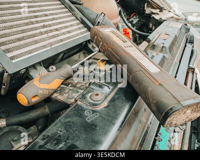 Riga, Latvia - March 31, 2026:Close-up of tools placed on a car engine under an open hood during repair. Shows real automotive maintenance work, diagn Stock Photo