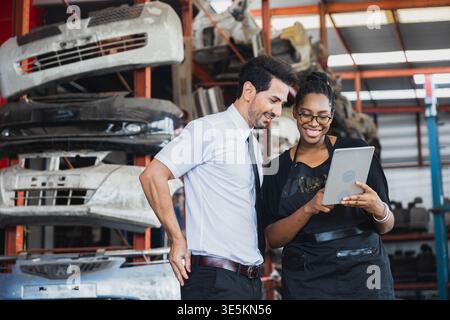 Diverse business partners using tablet to check auto parts in industrial warehouse storage Stock Photo