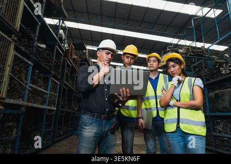Industrial workers and supervisor using laptops for meeting in warehouse storage facility Stock Photo