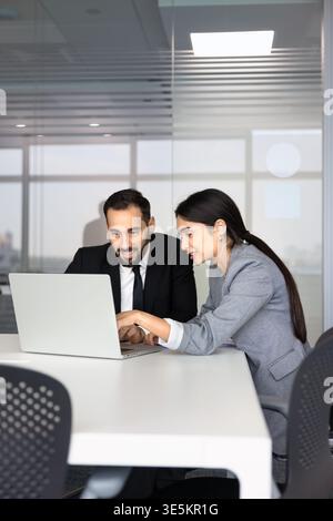 Diverse coworkers reviewing project details on laptop in corporate office Stock Photo