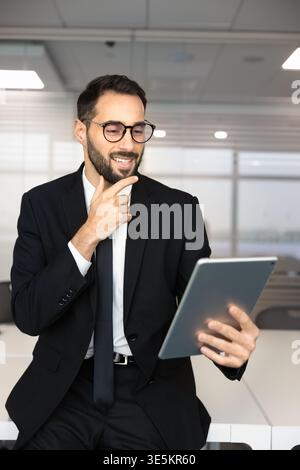 Smiling Hispanic businessman reviewing data on digital tablet Stock Photo