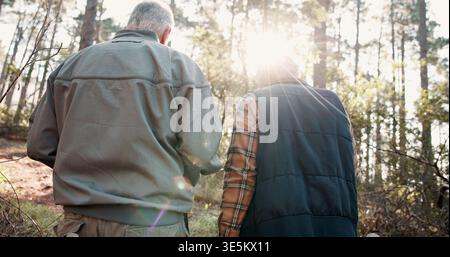 Hiking, walking and back of senior couple in forest for wellness, active hobby and fresh air. Travel, retirement and elderly man and woman on nature Stock Photo