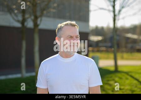 Portrait of a thoughtful mature man standing outdoors in warm sunlight looking into the distance. Stock Photo