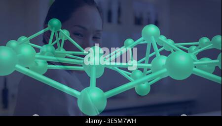 Studying researcher wearing white lab coat examining large teal molecular model in laboratory space Stock Photo