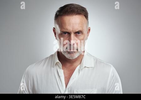 Business, man and serious anger in studio for unethical behavior, violation and disapproval. Space, mature manager and disappointed portrait on white Stock Photo