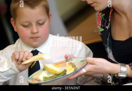 Primary school pupils having lunch with their peers and techers in a UK school. Stock Photo