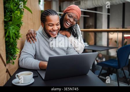 Happy black colleagues collaborating on laptop in office discussing work Stock Photo