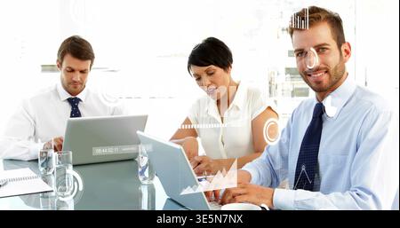 Smiling man on right in suit reviewing documents in office with laptop, data overlay, copy space Stock Photo