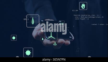 Holding hand in suit cuff displaying eco holographic icons over smartphone in dark studio with code Stock Photo