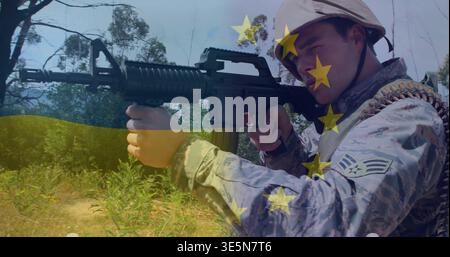 Aiming adult male soldier bracing M4 rifle in field, camo uniform ammo belt chevron flag overlay Stock Photo