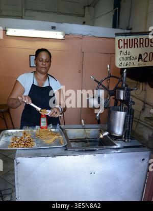 A Cuban woman preparing Churros in a small shop on Simón Bolívar Avenue in Havana, Cuba. Stock Photo