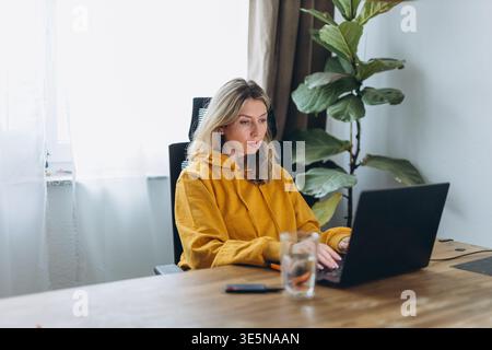 Focused woman working on laptop in home office showing deep work and productivity flow in calm remote lifestyle environment Stock Photo