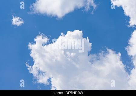 Fluffy cumulus clouds floating in a vibrant blue sky on a clear day Stock Photo
