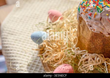 Easter cake with white icing and colorful sprinkles in basket with eggs festive spring composition Stock Photo
