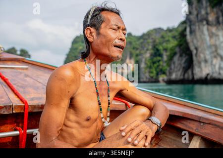 Thai senior man relaxing on traditional longtail boat Stock Photo