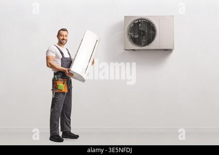 Worker installing indoor and outdoor air conditioning units Stock Photo