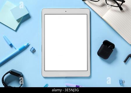 Tablet computer with different modern gadgets and stationery on blue background Stock Photo