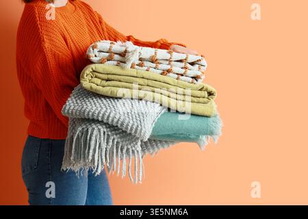 Woman holding warm plaids on orange background, closeup Stock Photo