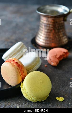 Plate with sweet macaroons on dark table Stock Photo