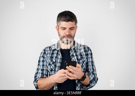Man Using Smartphone with Focused Expression Isolated on White Background. High quality photo Stock Photo