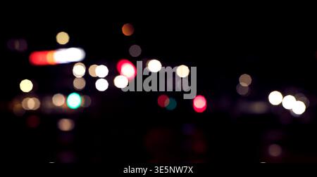 Abstract city lights at night with colourful bokeh and defocused blur. Urban background with glowing circles, soft illumination, and atmospheric night Stock Photo