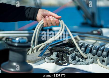 Hand working with rope and winch on sailboat deck Stock Photo