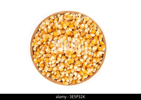 Dry yellow corn kernels fill a round wooden bowl on a white background Stock Photo