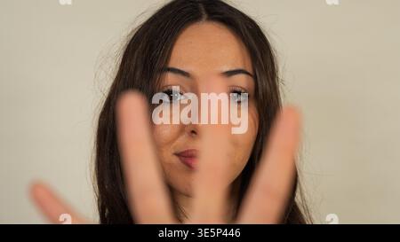 Young woman partially concealing face with a blurred hand, suggesting privacy and reluctance Stock Photo