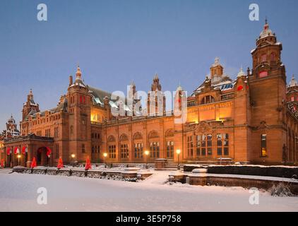Historic Kelvingrove Art Gallery in Glasgow illuminated at dusk, surrounded by fresh snow and festive Christmas lights, showcasing grand architecture, Stock Photo