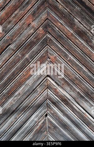Rustic weathered wooden planks arranged in a chevron pattern with aged texture and peeling paint. Stock Photo