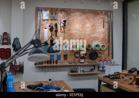 Well organized workshop with various tools and equipment hanging on wooden pegboard and arranged on workbenches, creating a dedicated space for Stock Photo