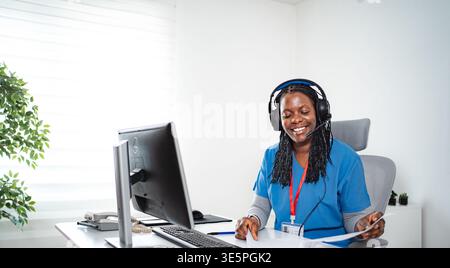 Healthcare professional working on computer, wearing headset Stock Photo