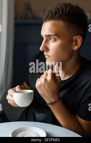 Handsome young man sitting and drinking aromatic coffee Stock Photo