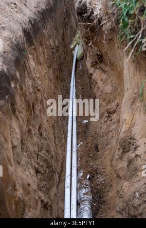 Insulated water pipe in earth trench, underground installing, utility line, site groundwork, plumbing protection, channel excavation, dirt covering, r Stock Photo