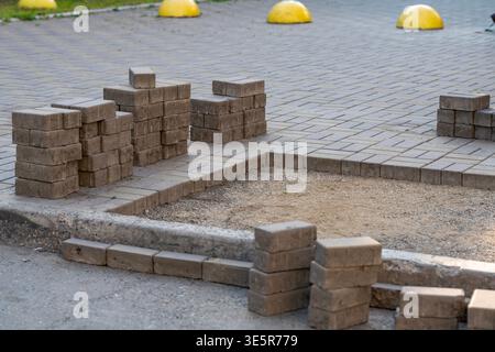 Stacks of rectangular paving bricks lined up next to a dug-out sidewalk area, showing urban pavement repair and outdoor walkway renovation with concre Stock Photo