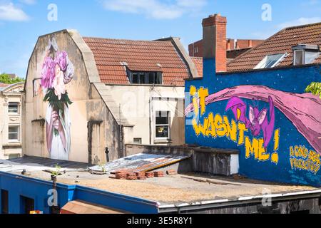 Colorful street art murals on the side of residential brick buildings under a blue sky in Bristol United Kingdom Stock Photo