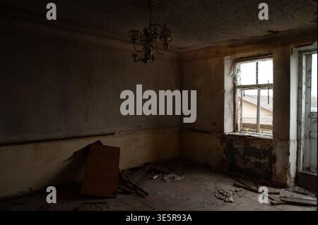 Abandoned Dilapidated Room With Peeling Paint Walls And Broken Windows Showing Decay In Dim Light Atmosphere Of Neglect Stock Photo