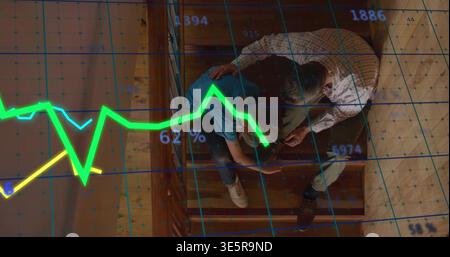 Holding phone middle-aged man in plaid shirt leaning toward boy viewing financial overlay on stairs Stock Photo