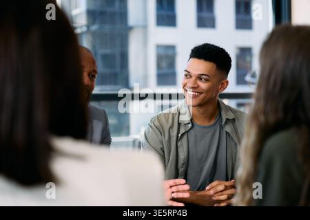 Smiling young businessman with colleagues having discussion in boardroom at office during daytime Stock Photo