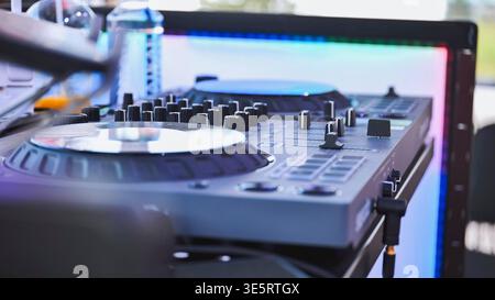 Dj set with mixer and colorful led panel lighting up the background Stock Photo