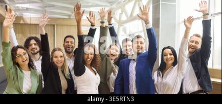 Diverse business team celebrating success with raised hands in modern office Stock Photo