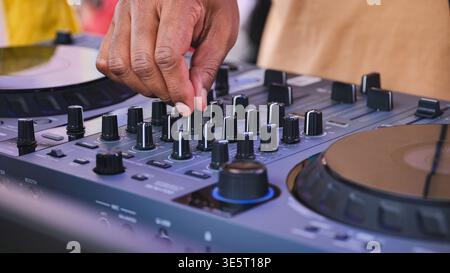 DJ hand adjusting controls on mixer for live music performance at an event Stock Photo